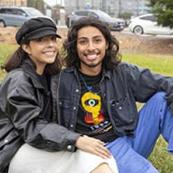 Two students sit together on the grass 