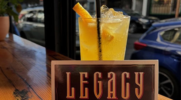 Drink with a promotional card about Legacy Bar